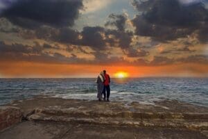 A couple standing on the beach at sunset.