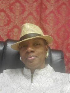 A man wearing a hat sitting in a chair.