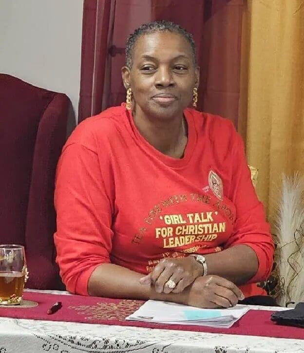 A woman sitting at a table with a glass of wine.