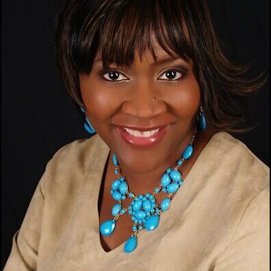 A woman with blue jewelry is smiling for the camera.